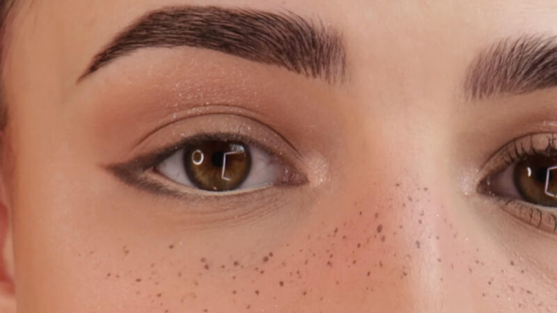 Close-up of eyes with soft, natural makeup and faux freckles, representing doe eye makeup